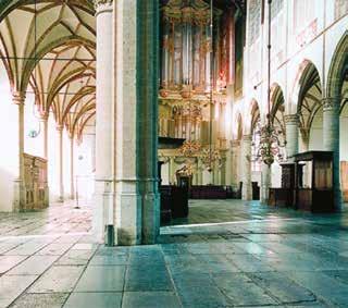 Interior view of a church featuring arches, columns, and a pipe organ.