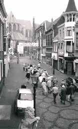 A historical procession with people walking down a street, honoring the miracle.