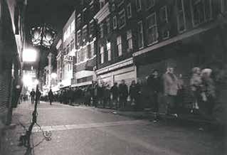 A nighttime procession with a long line of people walking down a street.