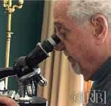 A scientist examining a sample under a microscope, focused on the details of the specimen.