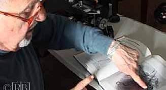 A man pointing at an image in a book, likely discussing scientific findings.