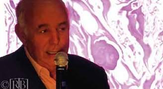 A man speaking into a microphone with a scientific image in the background.