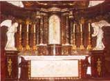 An ornate altar with two angel statues on either side and a central religious figure.
