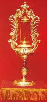 An ornate gold reliquary with intricate designs on a red background.