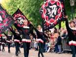 People in traditional costumes carrying large banners during a procession.