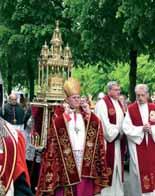 Clergy in ceremonial attire carrying a religious relic during a procession.