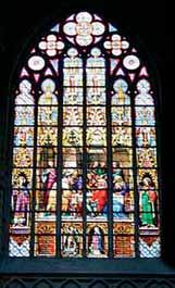 A stained glass window depicting the Eucharistic miracle with various figures and scenes.