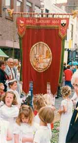 A banner depicting the Eucharistic miracle carried during a procession with children in white dresses.