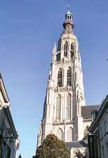 A tall church tower with intricate architectural details against a clear blue sky.