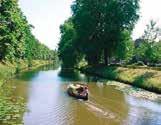 A serene canal scene with a boat surrounded by lush greenery and trees.