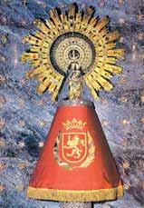 A statue of the Virgin of Pilar adorned with a golden sunburst and a red cape.