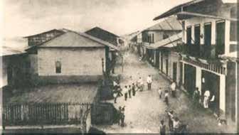 A historical street view of Tumaco with people and buildings, depicting the area during the early 1900s.