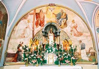 A religious altar with a statue of Mary surrounded by angels and floral arrangements.