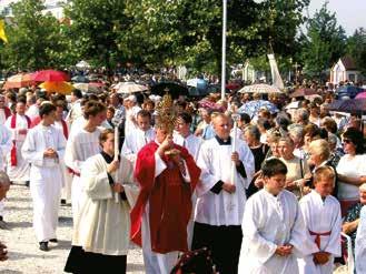 A religious procession with clergy and participants, celebrating a Eucharistic miracle in a crowded outdoor setting.