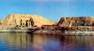 Image of ancient rock formations and temples near water, likely in Egypt.
