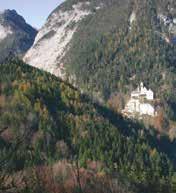 A distant view of a monastery nestled in a mountainous forested area.