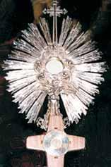 A silver monstrance displaying the miraculous Host, with intricate rays and a cross on top.