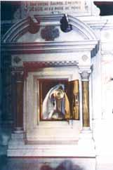 A tabernacle displaying the miraculous Host, featuring a statue of a figure in prayer.