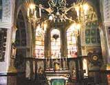 Interior view of a church with stained glass windows and altar.