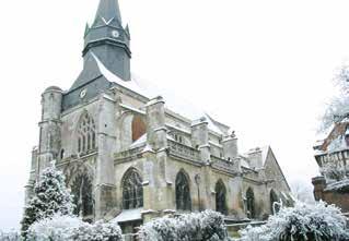 A snow-covered church with a tall steeple and gothic architecture.
