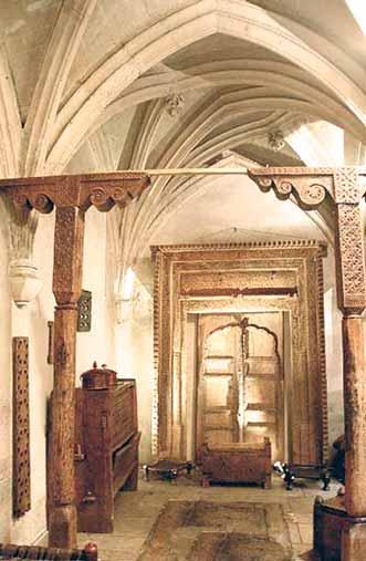 An ornate interior view of the cloister featuring intricate wooden carvings and arches.