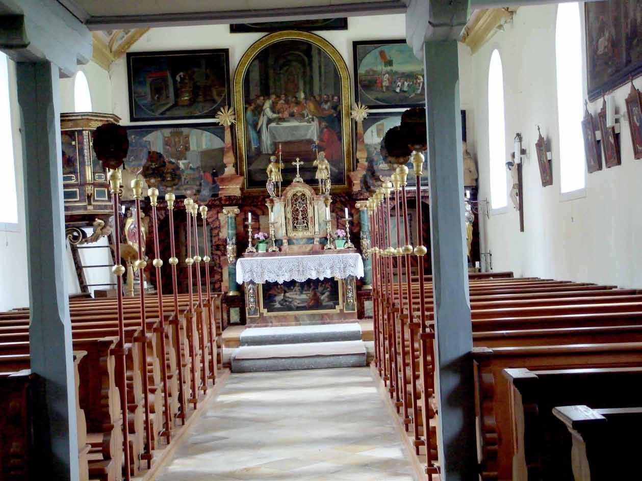 Interior view of a church featuring an altar with ornate decorations and wooden pews.