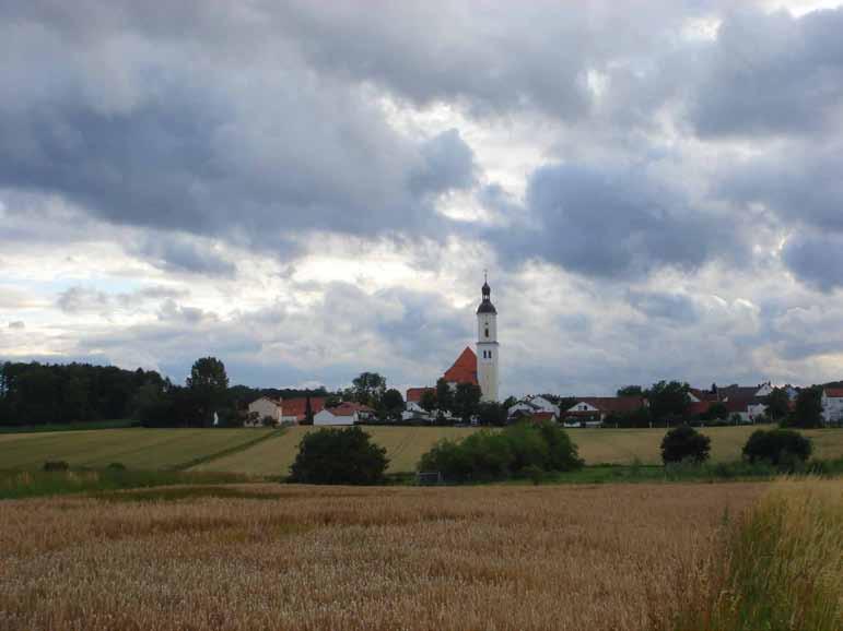 Bettbrunn village with its iconic church tower, site of the 1125 Eucharistic miracle, under a dramatic cloudy sky.