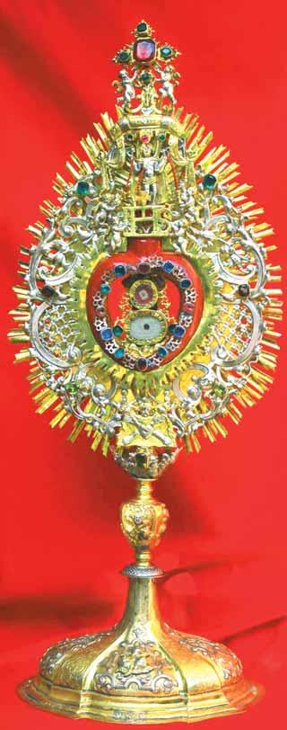A golden relic with intricate designs and a red center, symbolizing the Holy Blood.