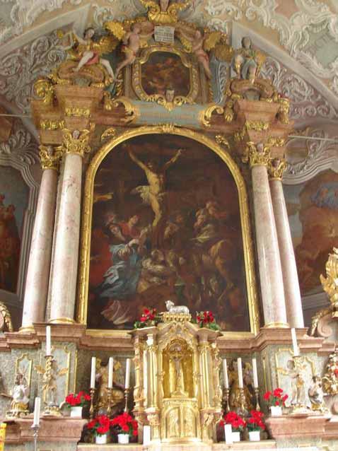 A richly decorated altar featuring a large painting of the crucifixion, surrounded by ornate details.