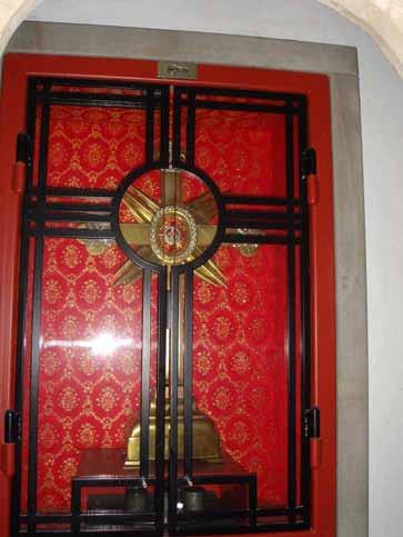 A reliquary with a golden Eucharistic monstrance, symbolizing the 1280 Kranenburg miracle, displayed behind a red patterned screen.