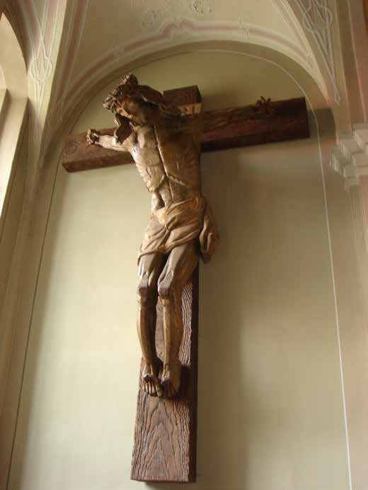A wooden crucifix depicting Jesus on the cross, mounted on a wall with an arched ceiling.