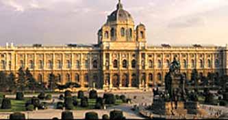 A large historical building with a dome and surrounding gardens.