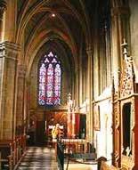 Interior view of a church featuring stained glass windows and architectural details.
