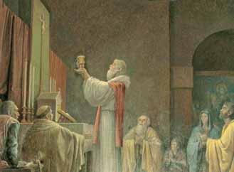 A priest holding a chalice during a religious ceremony, surrounded by clergy and onlookers.