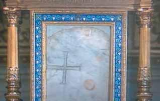 A decorated altar with a marble slab featuring a cross and circular stains.