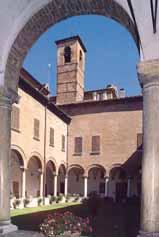 A courtyard view featuring a bell tower and arched columns in a historical building.