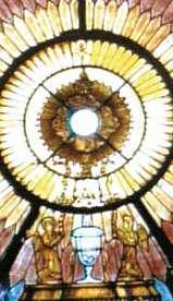 A stained glass depiction of the Eucharist with angels and a chalice.
