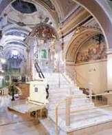 Interior view of a church with ornate architecture and a staircase.