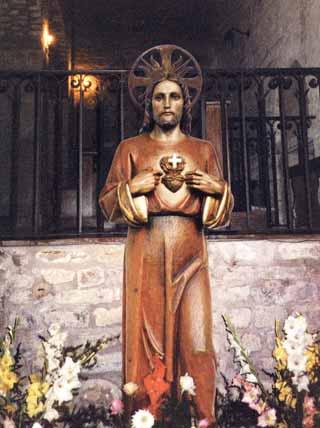 Statue of the Sacred Heart in Rosano, known for bleeding and weeping, surrounded by flowers, symbolizing post-war gratitude.