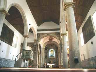 Interior of a church with arches, columns, and a wooden ceiling.