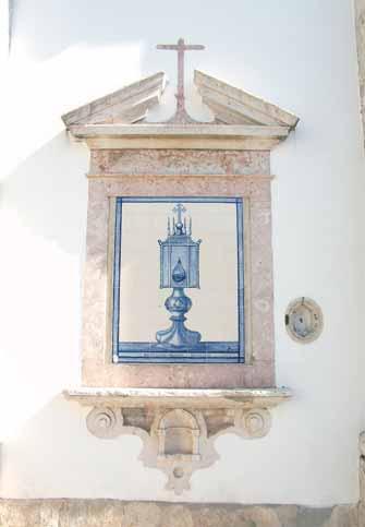 A decorative wall niche with a cross and an image of a glass ampulla, set in a stone frame.