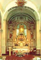 An ornate church altar with floral decorations and religious symbols, under an arched ceiling.