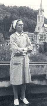 Alice Couteau, cured of multiple sclerosis during the Eucharistic procession, stands with Lourdes Basilica in the background.