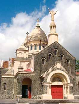 A stone church with a dome and statue on top, featuring a red door and arched windows.