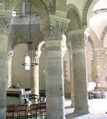 The image shows the interior of a basilica with stone columns and arches.