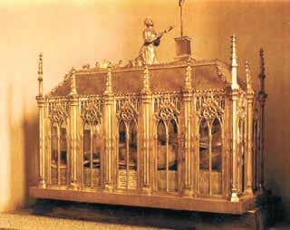 A golden tomb structure with intricate designs and a figure on top holding a cross.