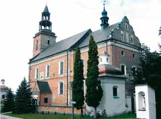 A brick church with two towers and surrounding trees under a clear sky.