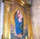 A painting of the Virgin Mary holding baby Jesus, surrounded by an ornate golden frame.