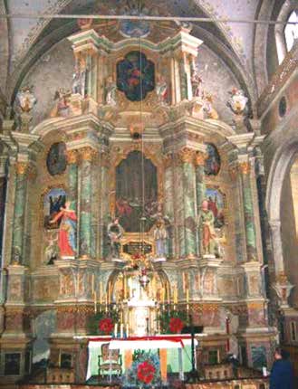 An ornate church altar with religious statues and paintings, featuring a central tabernacle.