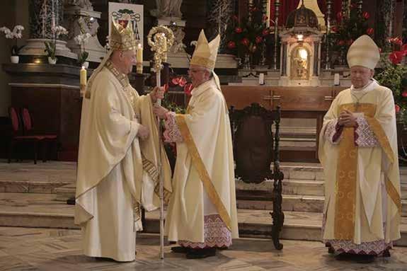 Three bishops in ceremonial attire during a religious event in a church setting.